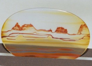 A pale yellow agate cabochon with bumpy orange bands that look like mountains or sand dunes.