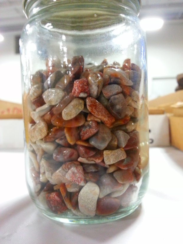 A clear glass jar full of small tumbled chips of Lake Superior agates.